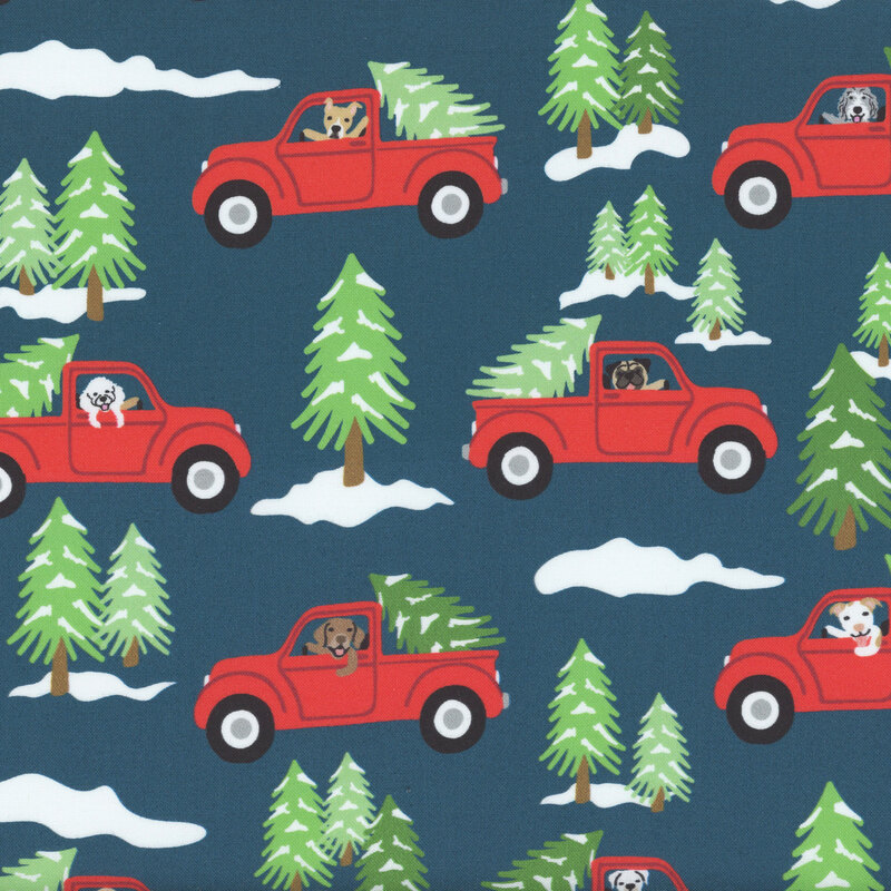 Indigo fabric with dogs driving red trucks carrying Christmas trees surrounded by snowy evergreen trees