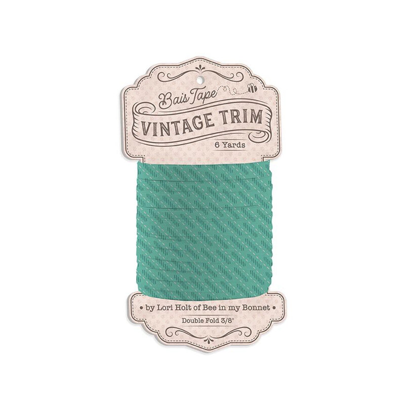 Spool of turquoise fabric with vertical white dashes and a pattern of dark teal lines bias tape isolated on a white background