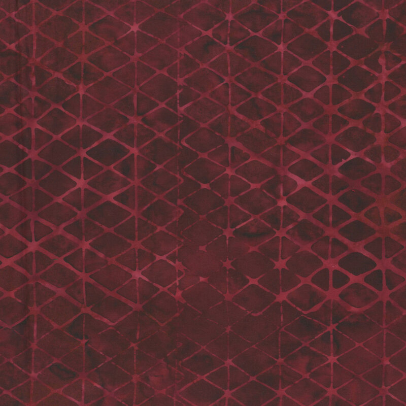A dark red batik fabric with geometric triangles and diamonds. 