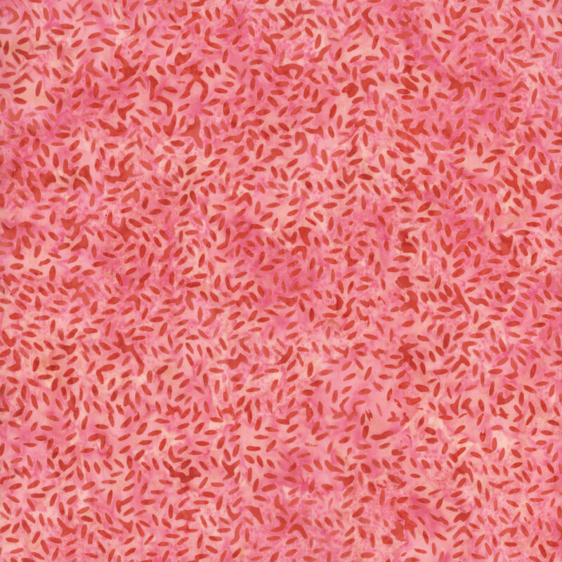 A candy pink batik fabric with red scattered speckles. 