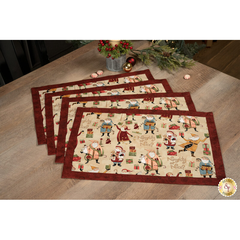 A shot of the four completed Christmas-themed overlapping placemats in the Santa print, staged on a wooden table with coordinating napkins and décor.