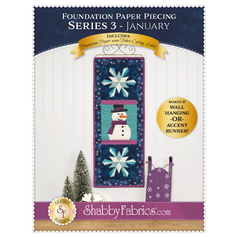 Front cover of the pattern showing the completed project, colored in navy, teal, purple, and white fabrics, hung on a craft hanger against a white paneled wall and staged with coordinating décor.