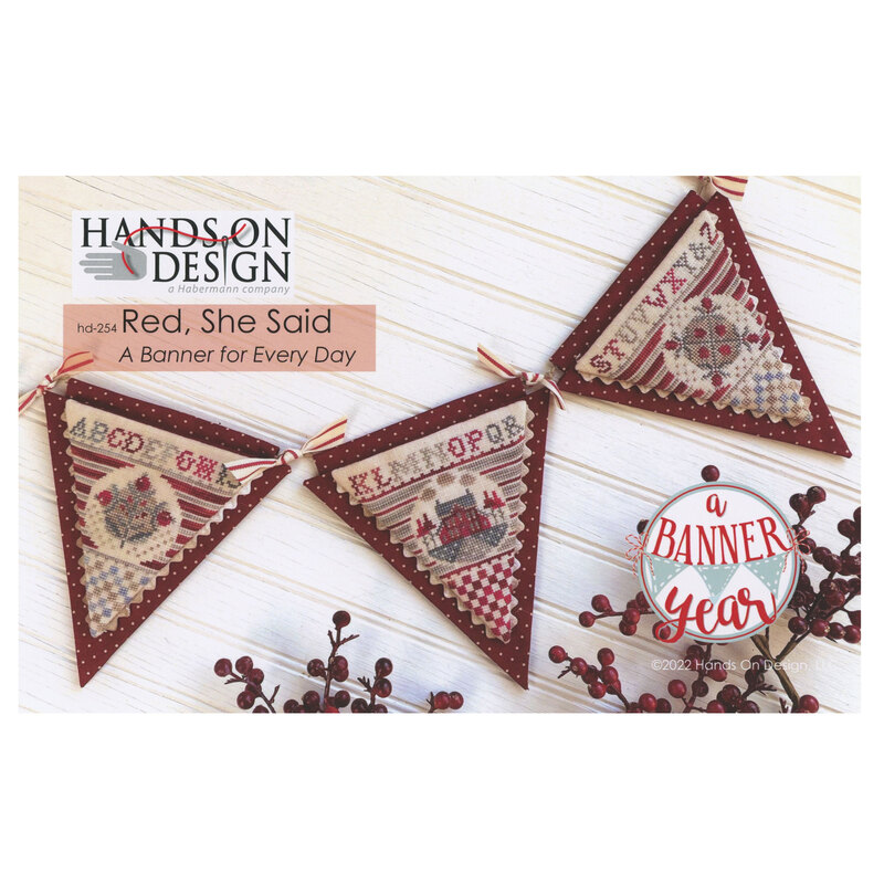 Front of pattern showing the completed cross stitch designs displayed on a white table with coordinating red berries.