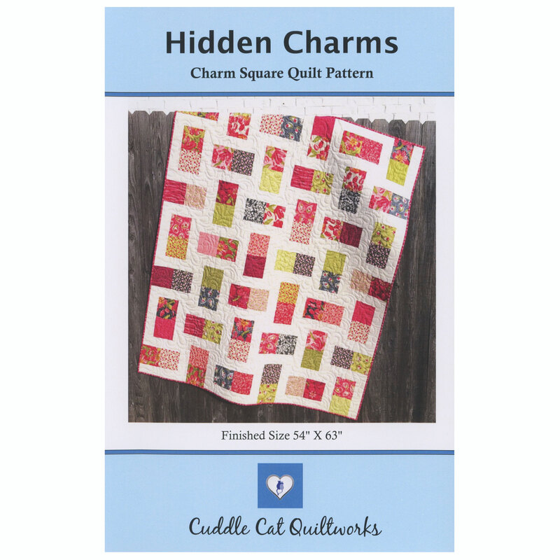 The front of the Hidden Charms quilt pattern displaying the finished product against a wood fence.