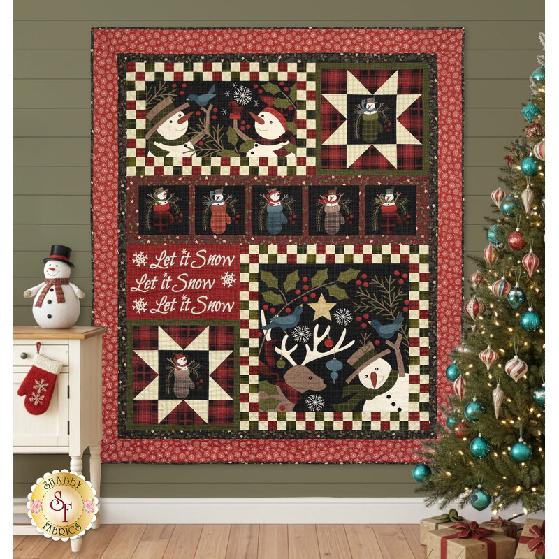The completed Let it Snow quilt, colored in red, black, cream, and green flannels from the Holly Jolly fabric collection, hung on a green paneled wall, the quilt is staged with coordinating winter themed decor and furniture.
