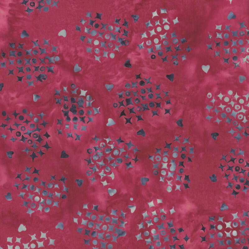 Mottled pomegranate red fabric with a heart shaped pattern of x's and o's with interspersed hearts in indigo, and light blue
