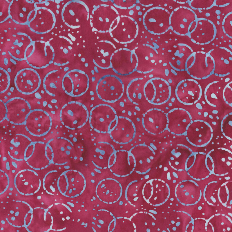 Mottled rose red fabric with a pattern of white and blue watercolor circles and drops