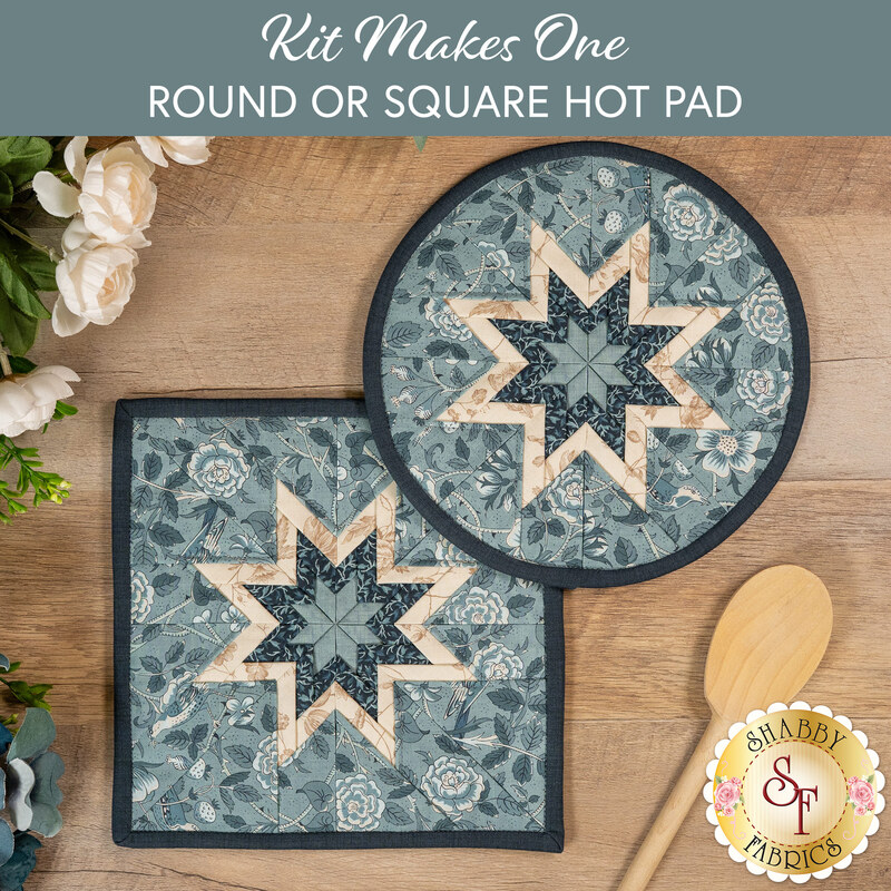 The two completed medium blue Folded Star Hot Pads, one round and one square, slightly overlapping each other and staged on a wooden table with coordinating décor.