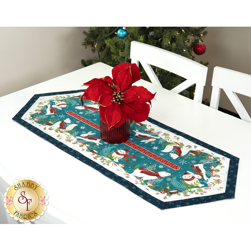 A shot of the runner staged on a bright white table with a red basket of red and gold poinsettias in the center.