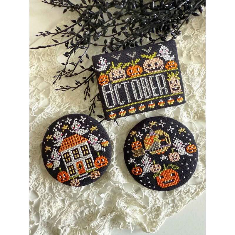 A Halloween-themed collection of cross stitch projects that features coasters with a house and pumpkins, alongside a card that reads October.