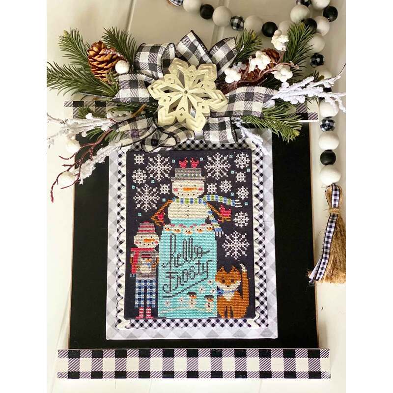 A decorative cross stitch pattern for winter featuring a snowman, a nutcracker, a fox, and festive greenery with a bow.