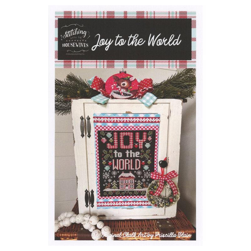 The front of the Joy To The World cross stitch pattern showing the completed project surrounded by coordinating holiday décor. 