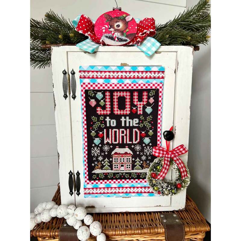 A decorated cabinet with a festive Joy to the World sign, wreath, and pine garland.