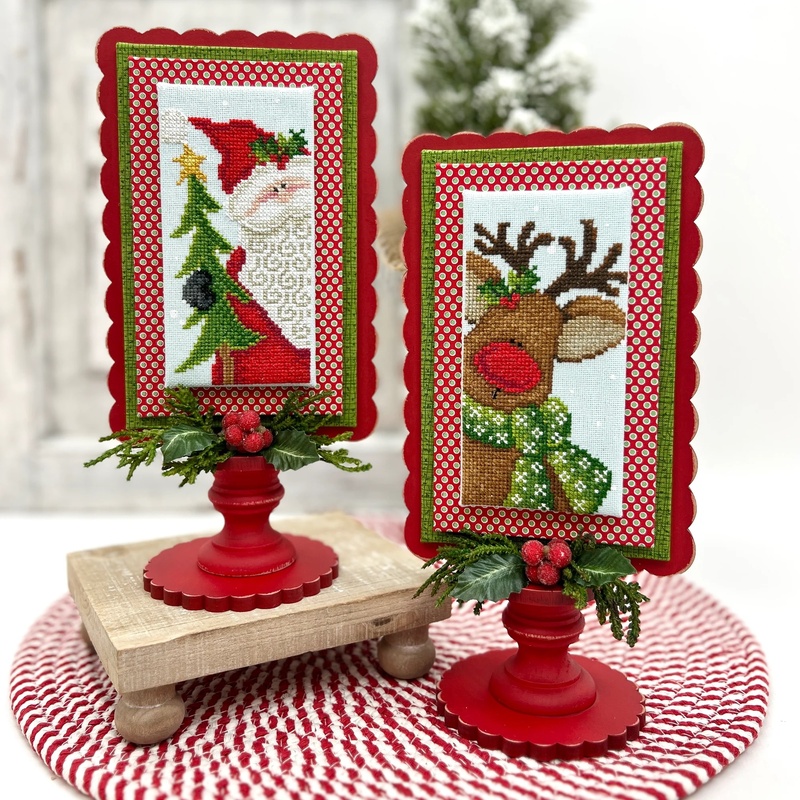 The fully assembled and painted Simply Scallop Rectangle Pedestal Frame, staged on a tabletop with coordinating winter decor, displaying a Santa and Rudolph-themed project.