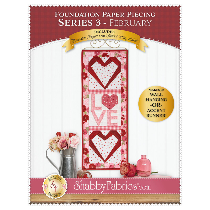 Front cover of the pattern, showing the completed project in cute shades of red, pink, and white fabrics, hung on a craft display hanger against a while paneled wall and staged with coordinating décor.