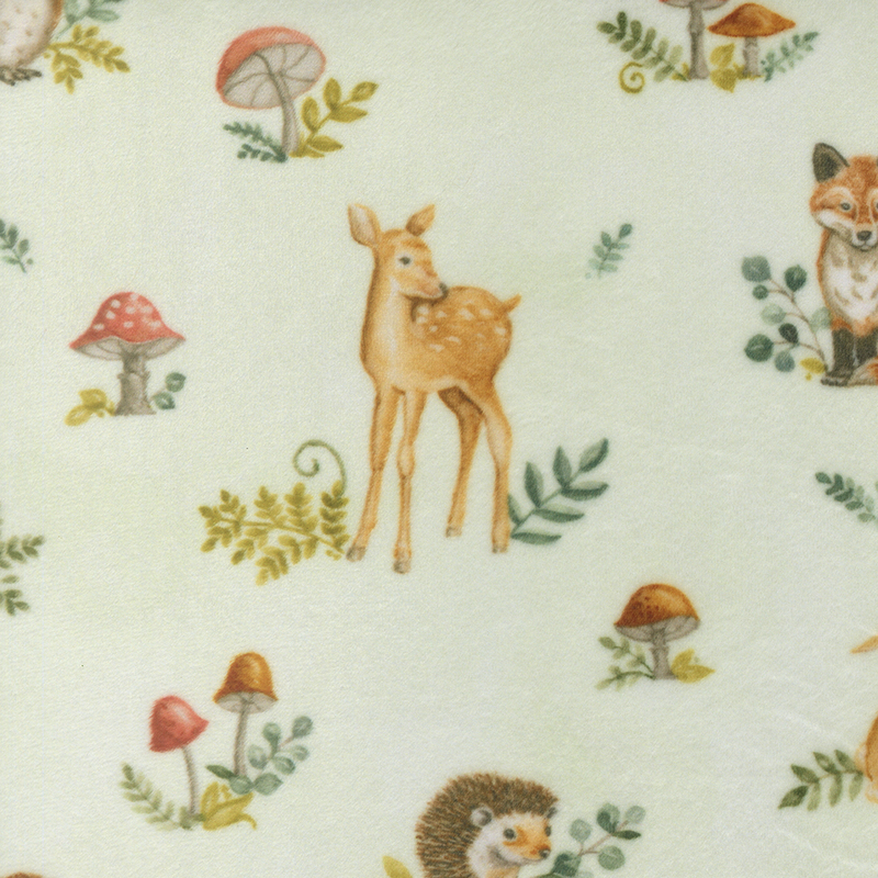 Soft green fabric with a pattern of forest animals, mushrooms, and foliage.