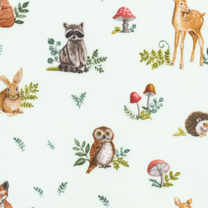 Mint green fabric with a pattern of forest animals, mushrooms, and foliage.