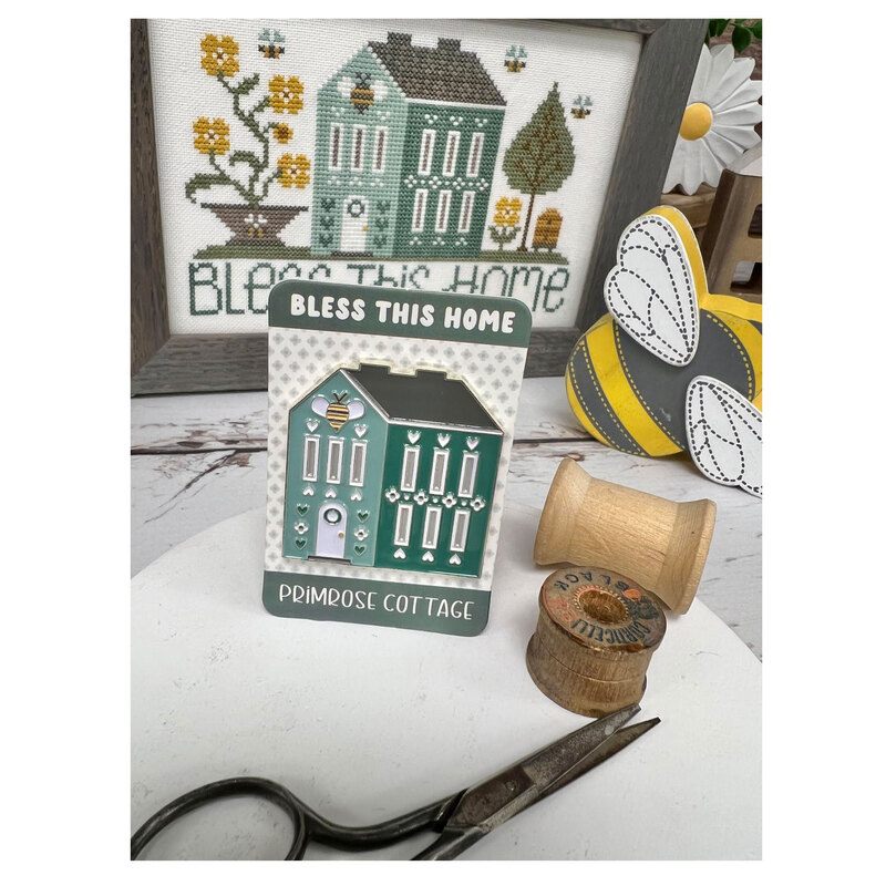 The Bless This Home needle minder, stood up on a table with embroidery scissors, a spool of thread and coordinating décor.