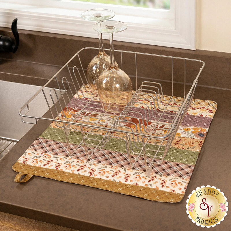 The completed Dry Ideas drying mat, colored in humble summer fabrics from the Evening on the Prairie collection. The project is staged on a kitchen counter with coordinating decor.