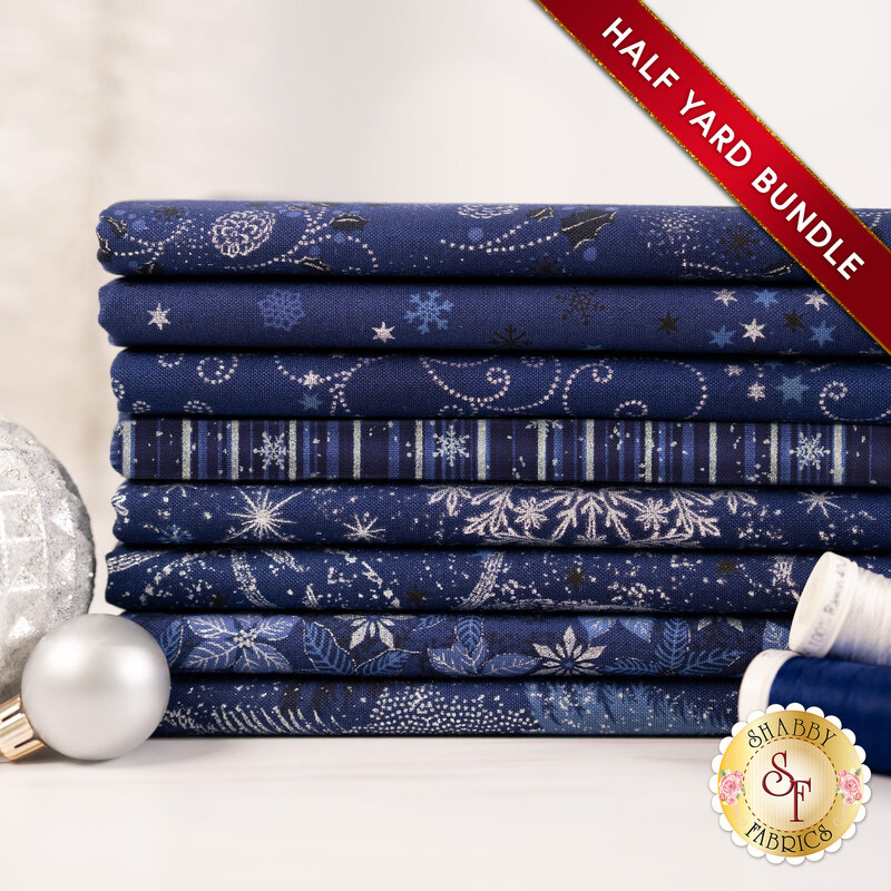 A stack of the eight fabrics included in the 8 HY Bundle Dark Blue/Silver by Stof Fabrics, staged with thread and ornaments.