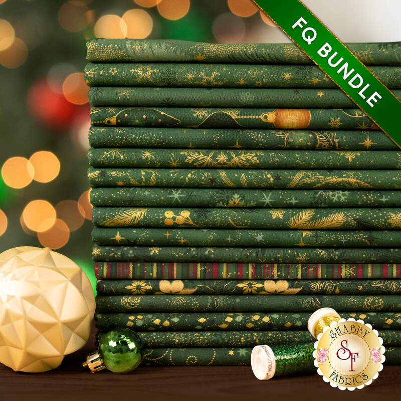 A stack of the seventeen fabrics included in the 17 FQ Bundle Green/Gold by Stof Fabrics, staged with ornaments and thread.