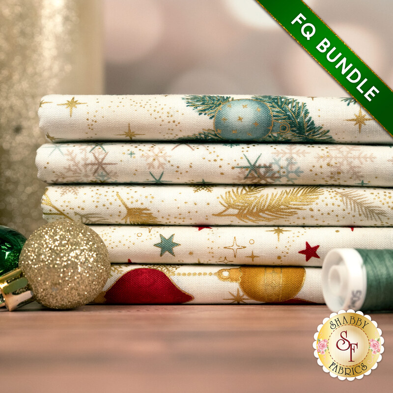 A stack of the five fabrics included in the 5 FQ Bundle Cream Green/Gold by Stof Fabrics, with ornaments, thread, and a candle.