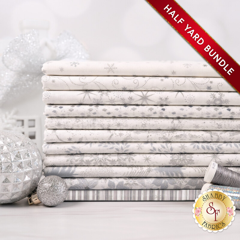 A stack of the eleven fabrics included in the 11 HY Bundle White/Silver by Stof Fabrics, staged with thread and ornaments.