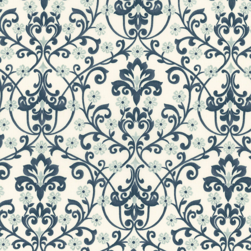 A cream damask fabric with blue scrolling florals, vines, leaves, and ornamental motifs. 