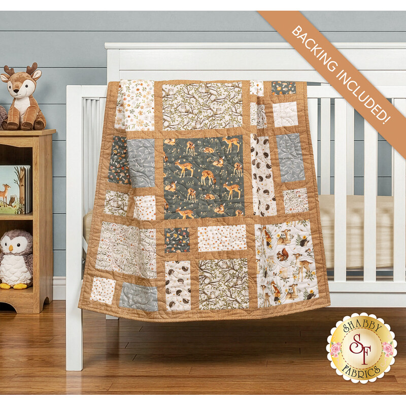 A patchwork quilt in neutral brown, gray, and tan tones from the Count on Me collection draped over a white crib, set with coordinating baby toys and decor. 