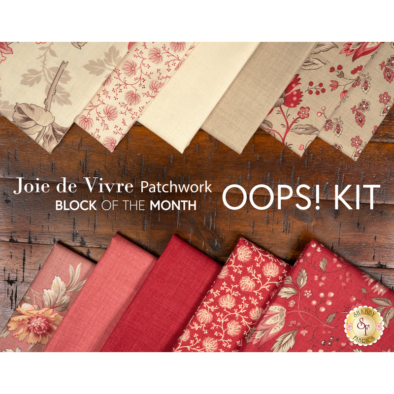 The fabrics included in the Joie de Vivre Patchwork BOM, fanned out in the red and cream colorways on a dark wood table; in between the rows of fabric, a text graphic reads "Joie de Vivre Patchwork Block of the Month Oops! Kit."