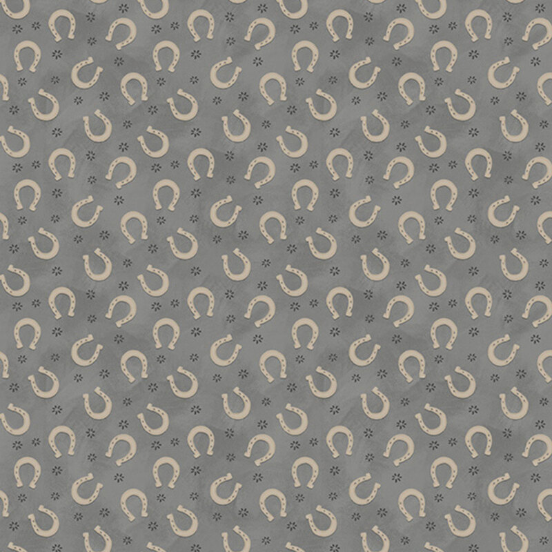 Mottled gray fabric with a tossed pattern of cream horseshoes and abstract spurs.