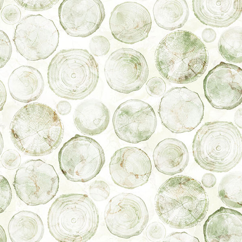 Mottled, off-white fabric featuring the stamped images of tree rings of various sizes in shades of green.