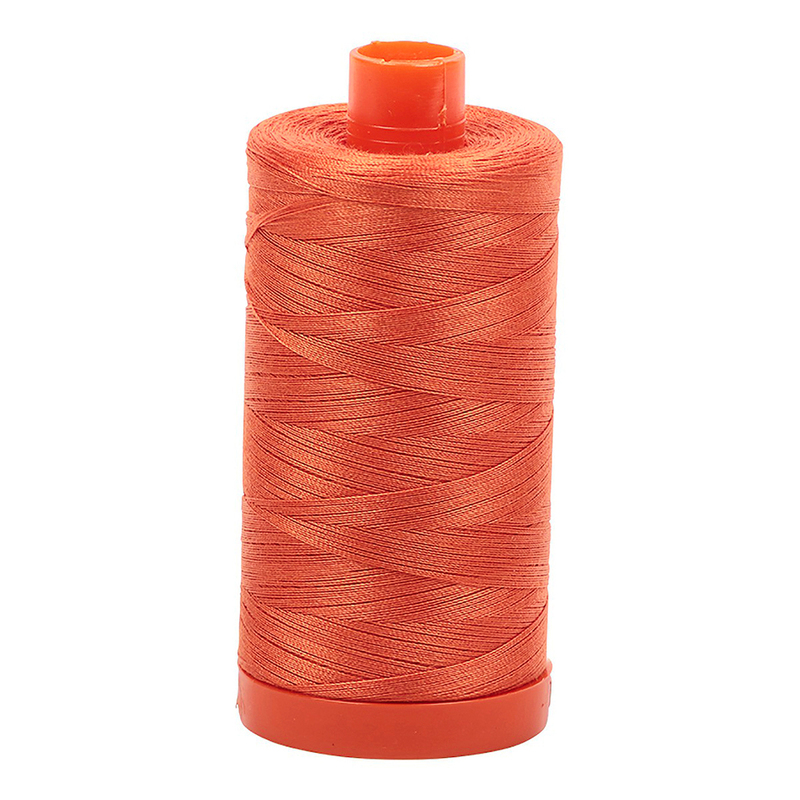 A spool of Aurifil 1154 - Dusty Orange thread on a white background