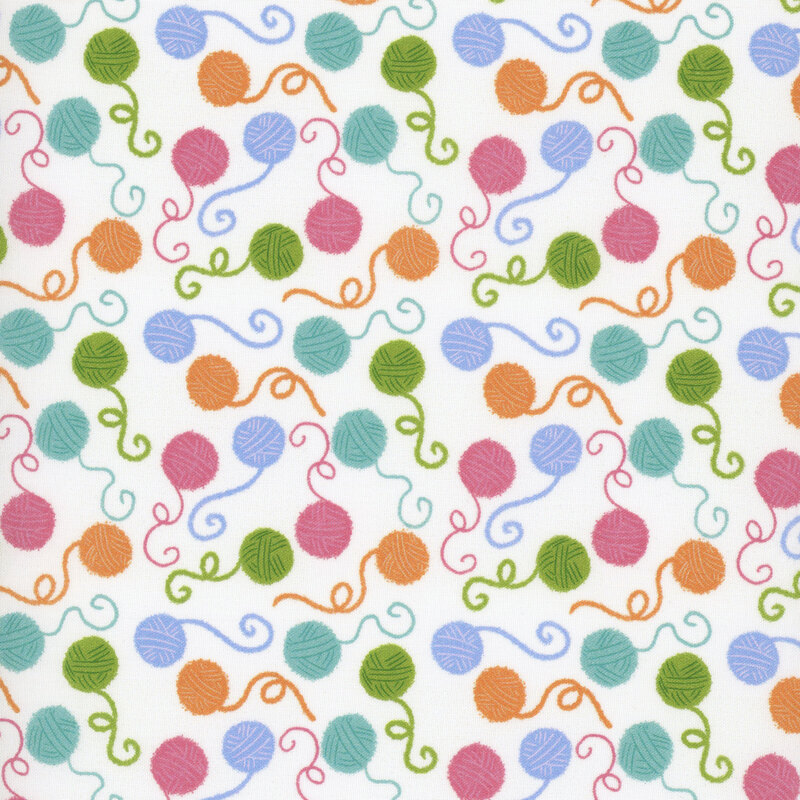 White fabric featuring colorful balls of unspooling yarn.