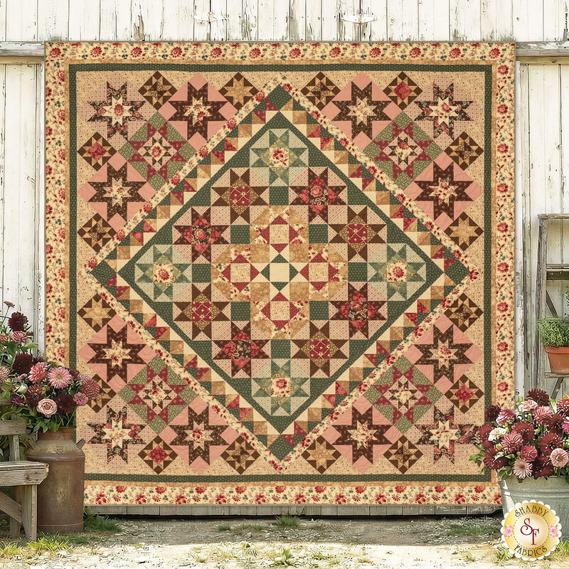 The completed Blooming Beauty quilt, colored in powder pink, avocado green, warm tan, and cocoa brown fabrics from the Always and Forever collection, hung on a rustic wood paneled wall and surrounded by coordinated décor.