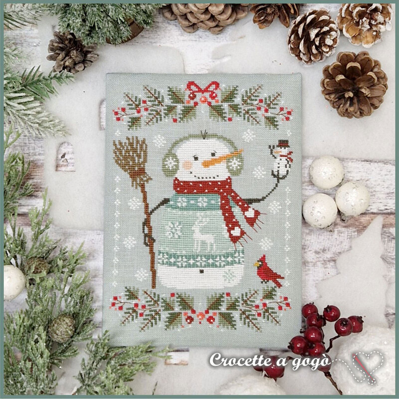 The completed project, a warmly dressed snowman in a light blue sweater, staged with coordinating winter and holiday decor.