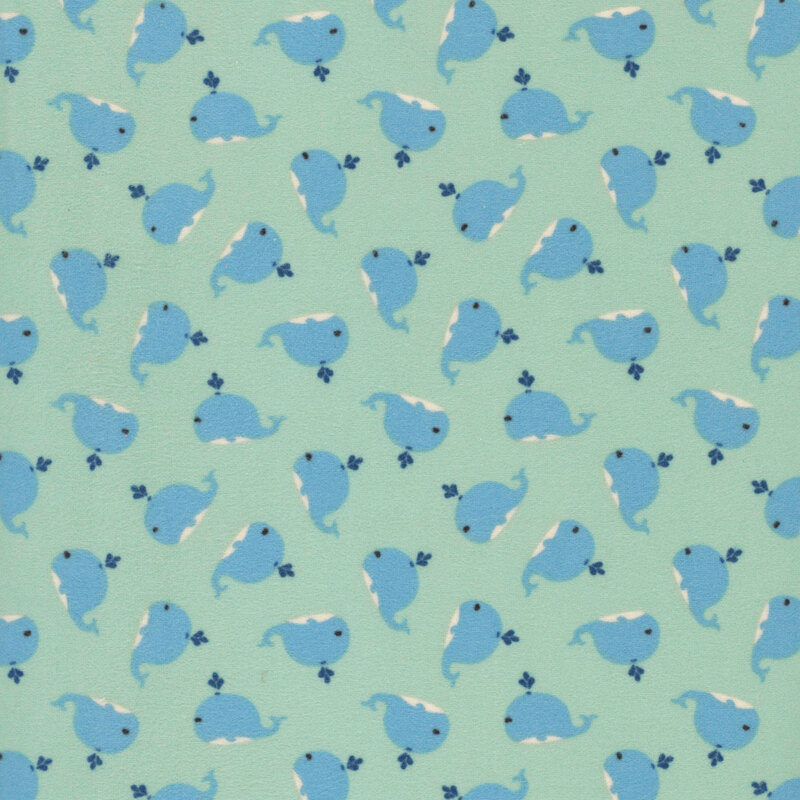 Light teal fabric with tiny variegated pindots and a ditsy pattern of cute blue whales