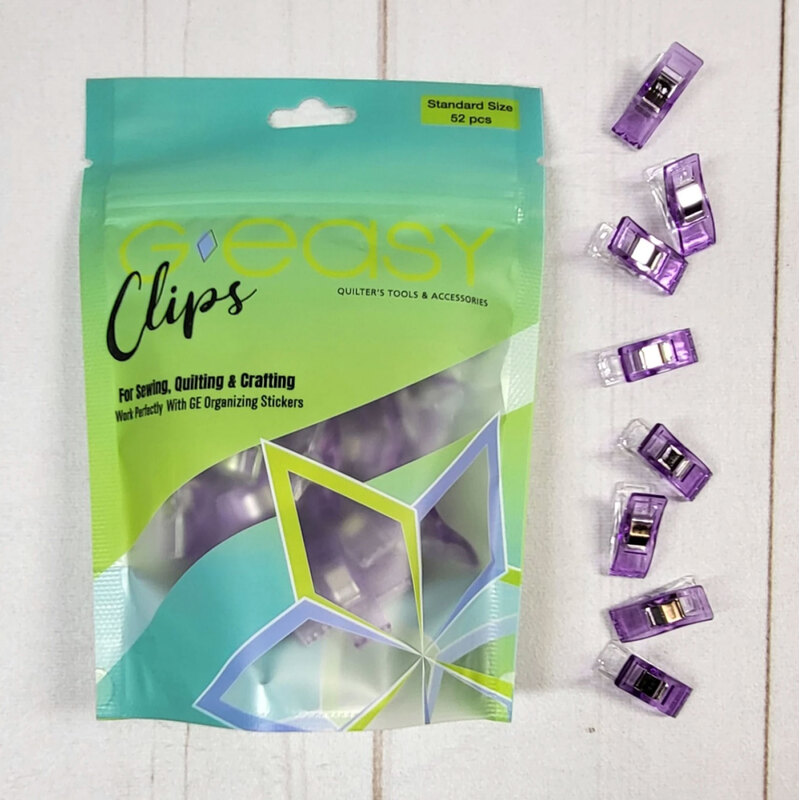 Clear packaging of Easy Clips for sewing, quilting, and crafting, with pruple clips displayed around it.