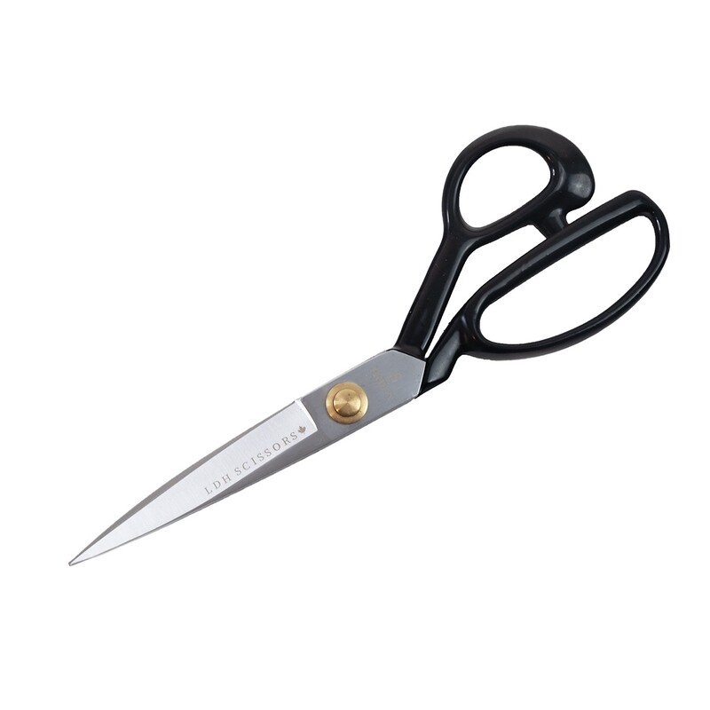 A pair of stainless steel scissors with black handles, featuring a gold pivot screw.