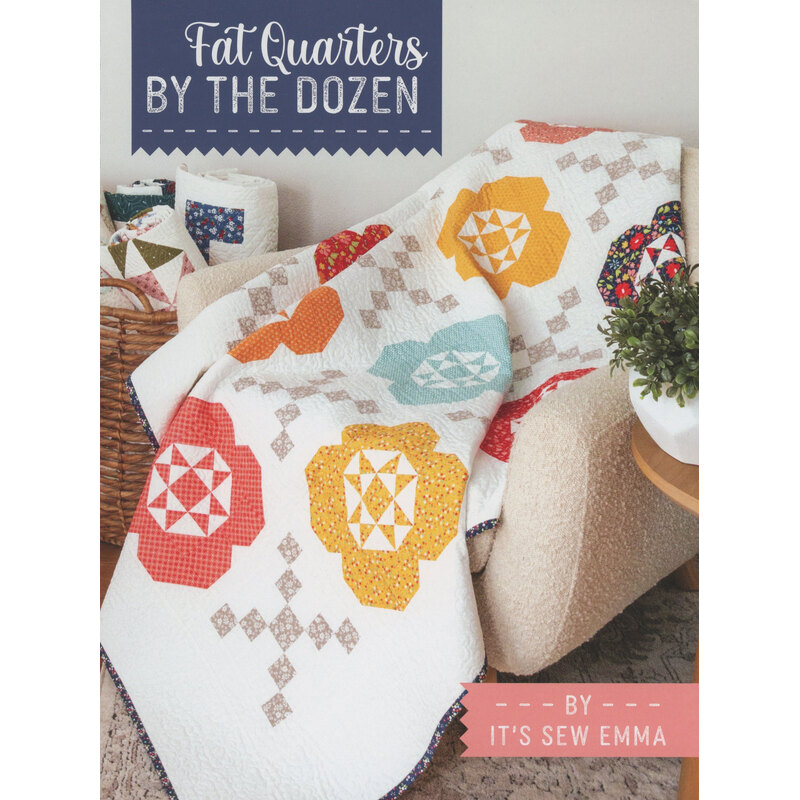 The front cover of the Fat Quarters By The Dozen book featuring a colorful quilt draped over a chair, featuring floral patterns in red, orange, and blue.