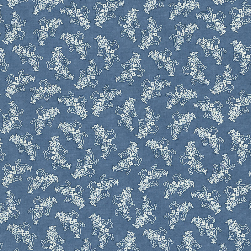 Denim blue fabric with a pattern of ornamental navy blue and white floral motifs