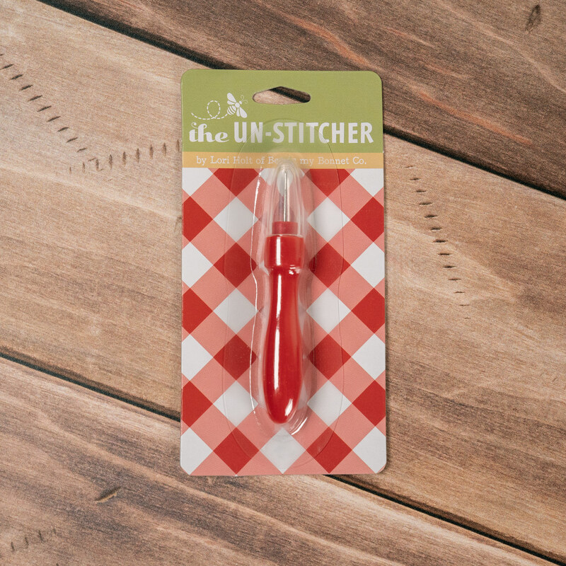 The Un-Stitcher by Lori Holt in red gingham packaging on a wooden background