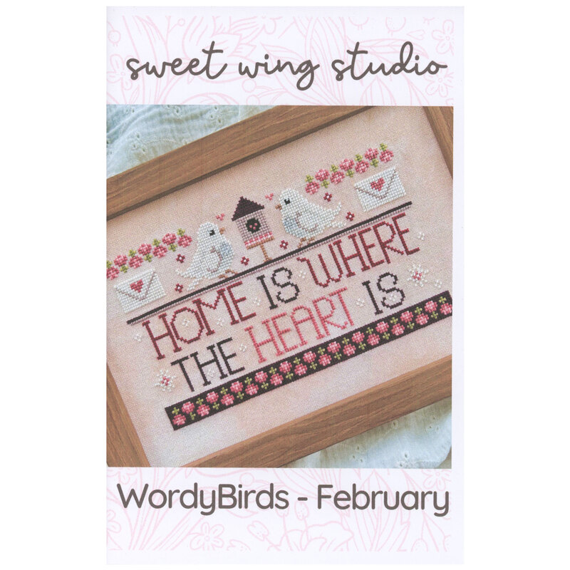 The front of the WordyBirds - February cross stitch pattern featuring the completed project in a wood frame.
