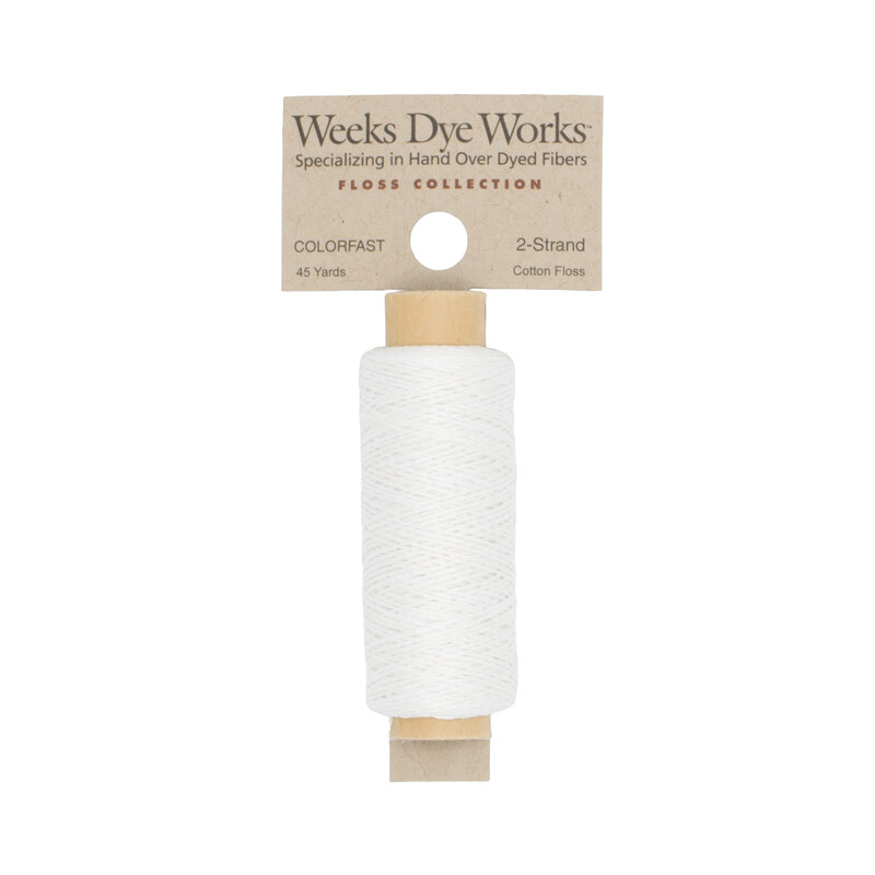 A spool of white embroidery floss with a tan label featuring the brand name and color information.