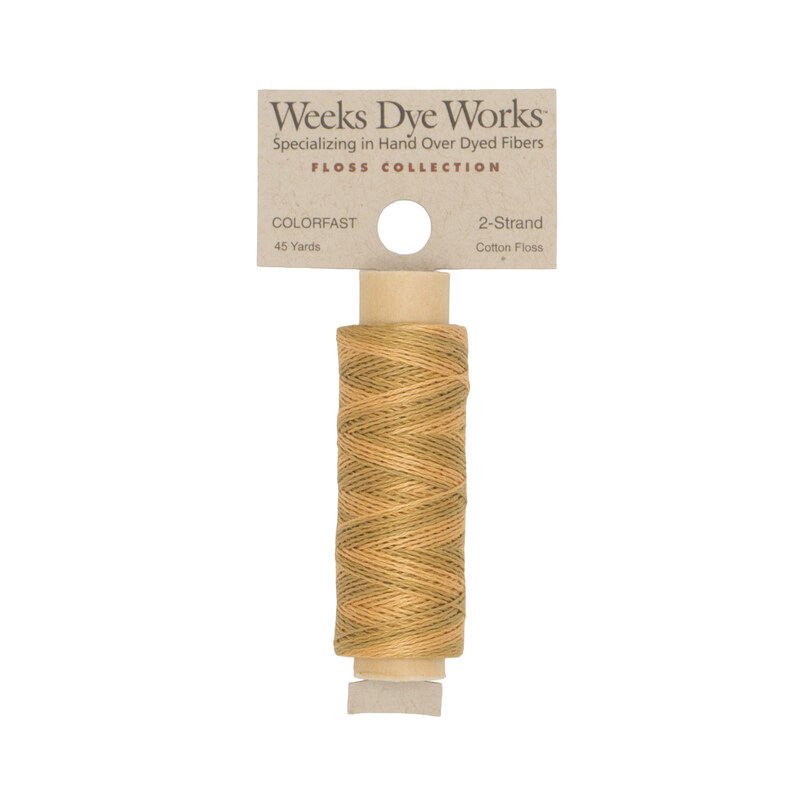 A spool of straw gold embroidery floss with a tan label featuring the brand name and color information.