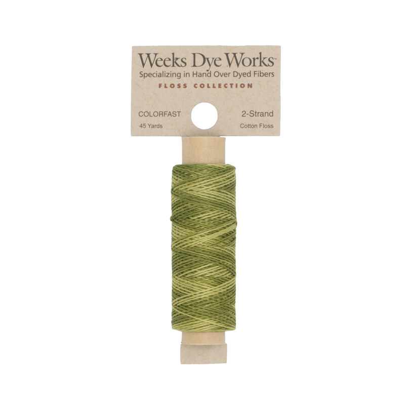 A spool of tonal green embroidery floss with a tan label featuring the brand name and color information.