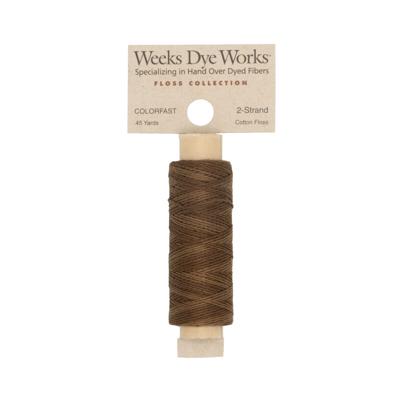 A spool of nut brown embroidery floss with a tan label featuring the brand name and color information.