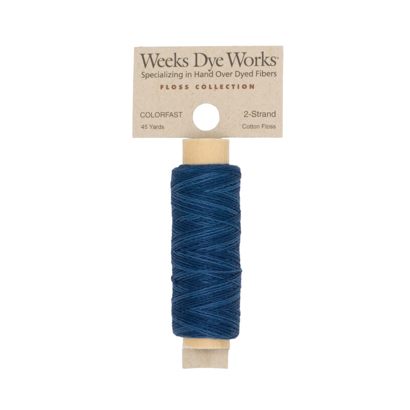 A spool of dark blue embroidery floss with a tan label featuring the brand name and color information.