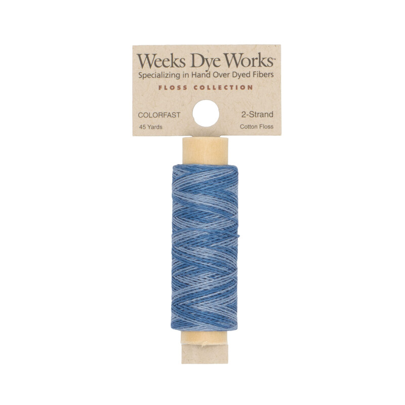 A spool of sky blue embroidery floss with a tan label featuring the brand name and color information.