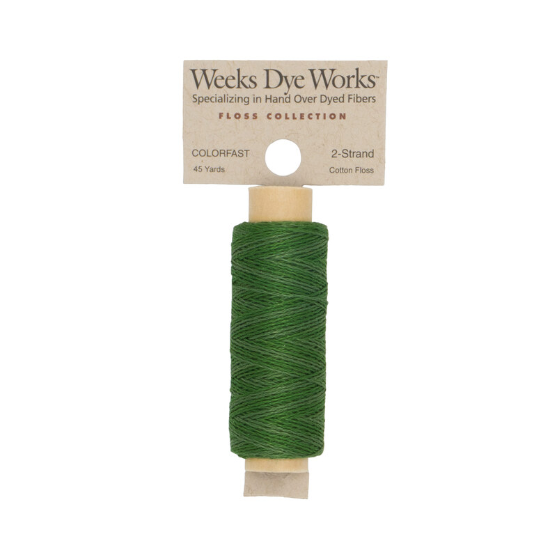 A spool of green embroidery floss with a tan label featuring the brand name and color information.
